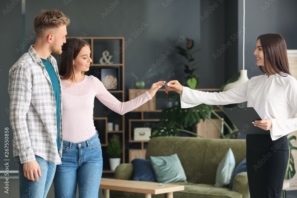 Real estate agent giving a key from new house to young couple