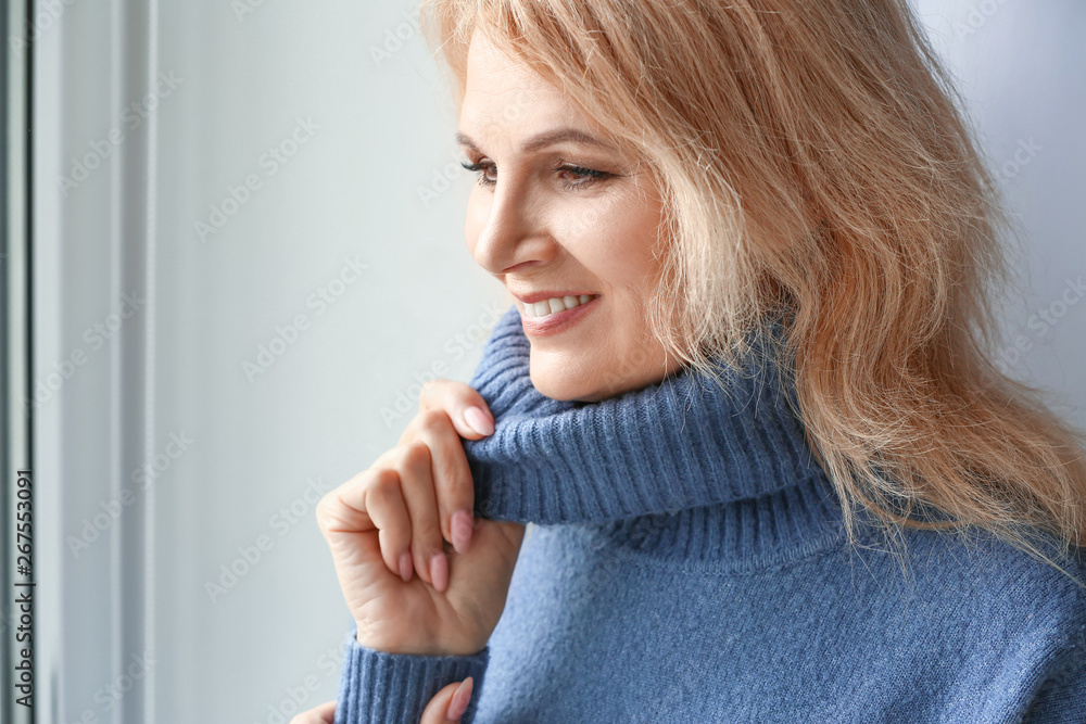 Portrait of beautiful mature woman near window at home