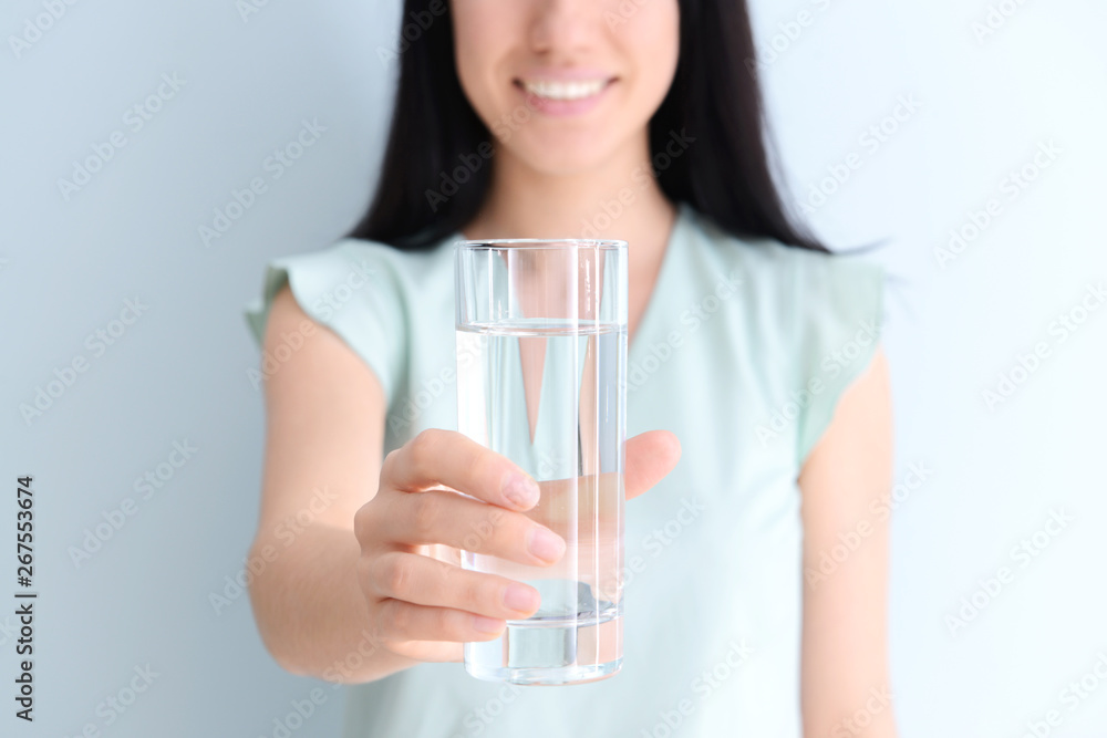 Woman with glass of fresh water on light background