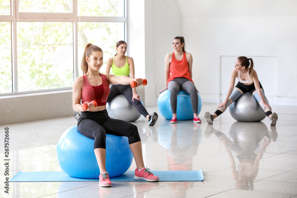 Young sporty woman doing exercises with fitball in gym