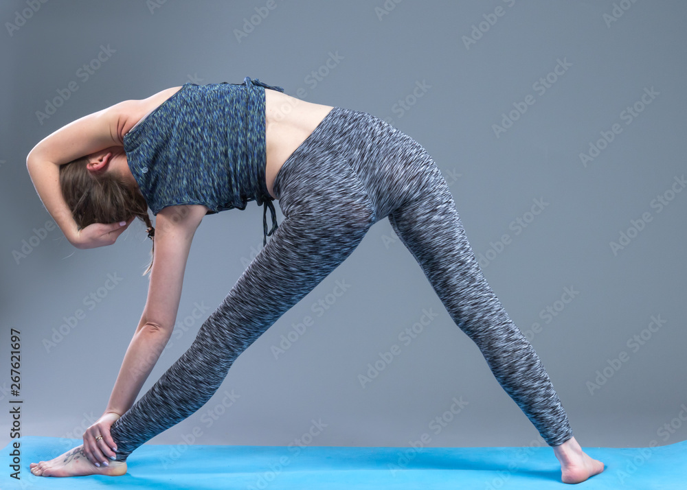 Beautiful sporty fit young woman practices yoga asana.