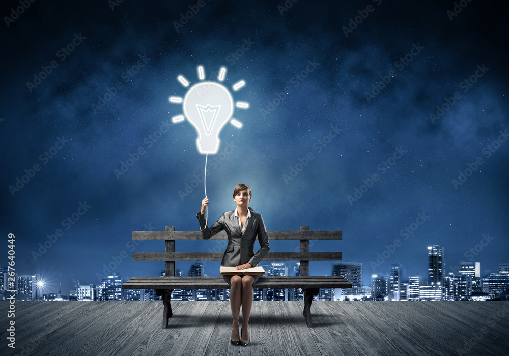 Young woman holding open book on bench