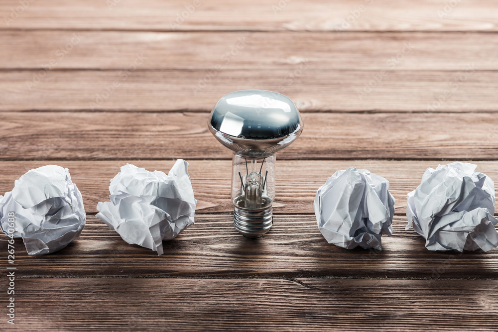 Ideological concept with wastepaper light bulb on wooden table