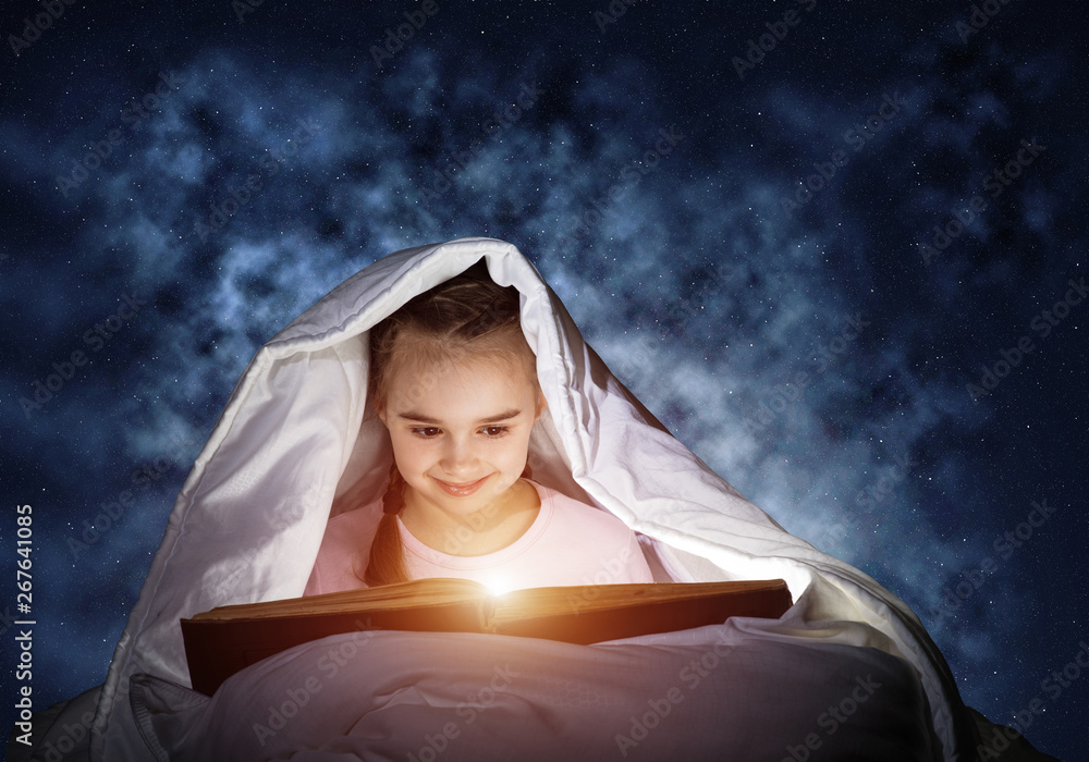 Engrossed little girl reading book in bed