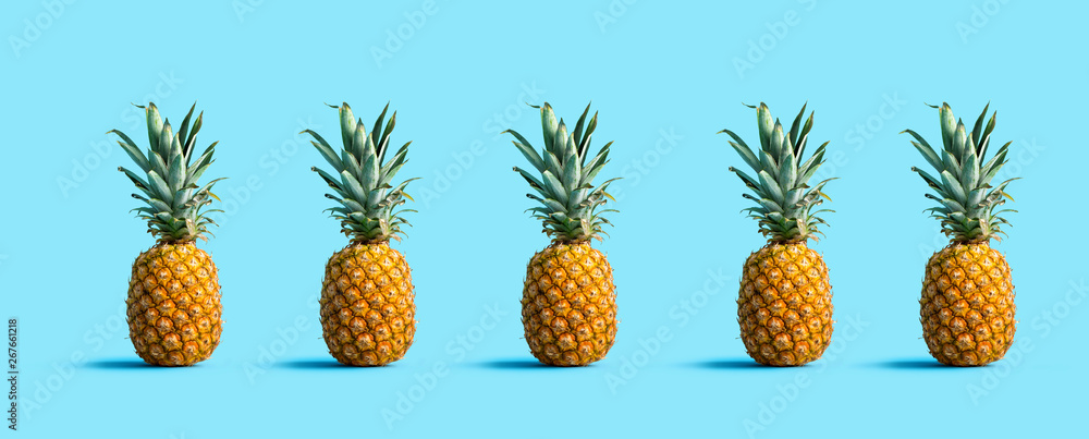 Many pineapples on a solid color background