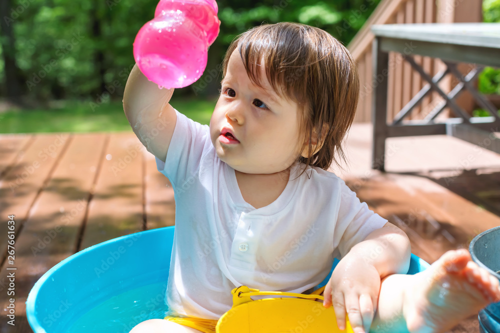 Young toddler boy playing with water outside