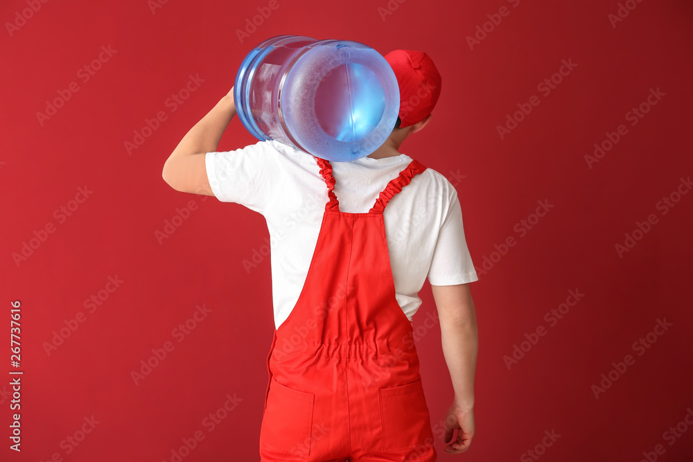 Asian delivery courier with bottle of water on color background, back view