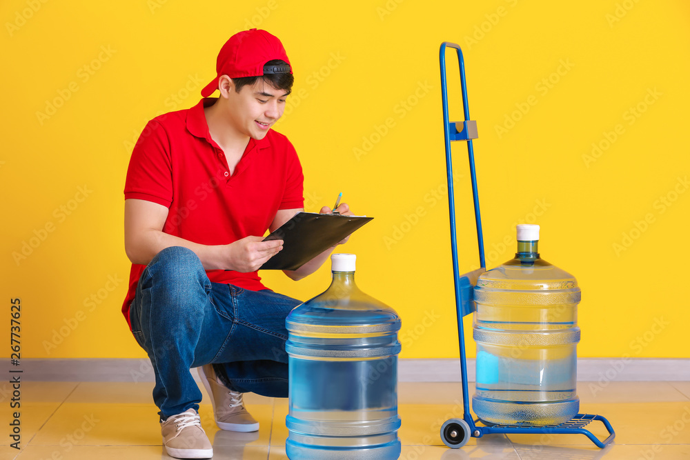 Asian delivery courier with bottles of water and clipboard indoors