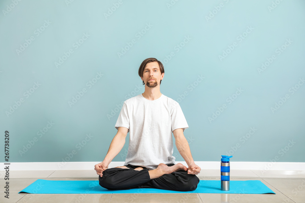 Sporty man practicing yoga indoors