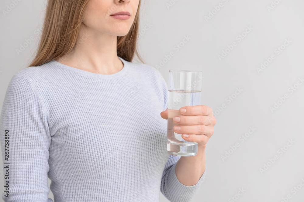 Woman with glass of fresh water on light background