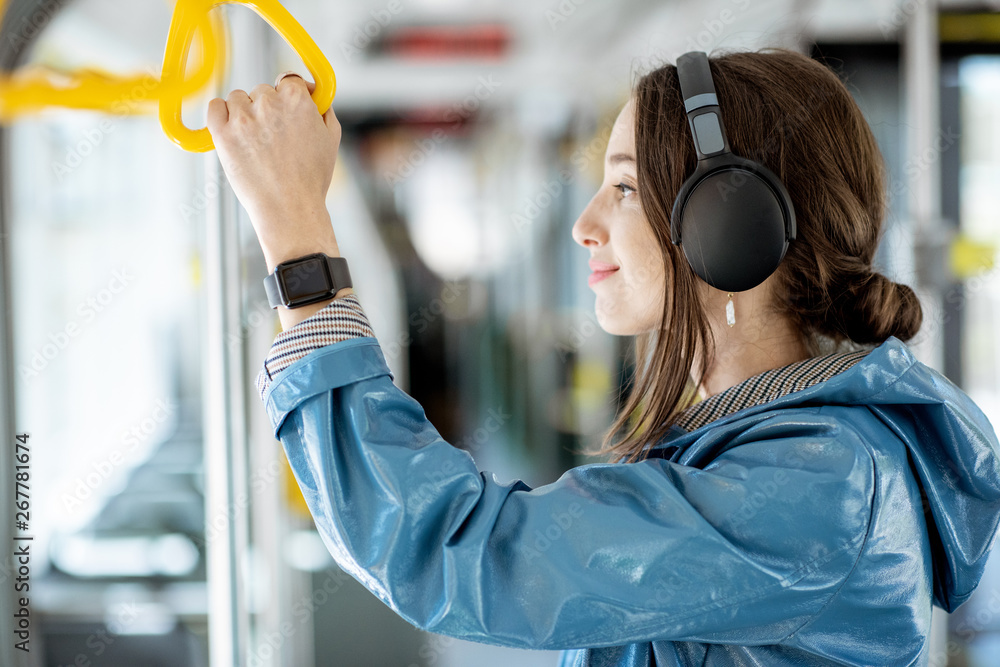 Young woman holding handle while moving in the modern tram. Happy passenger enjoying trip at the pub