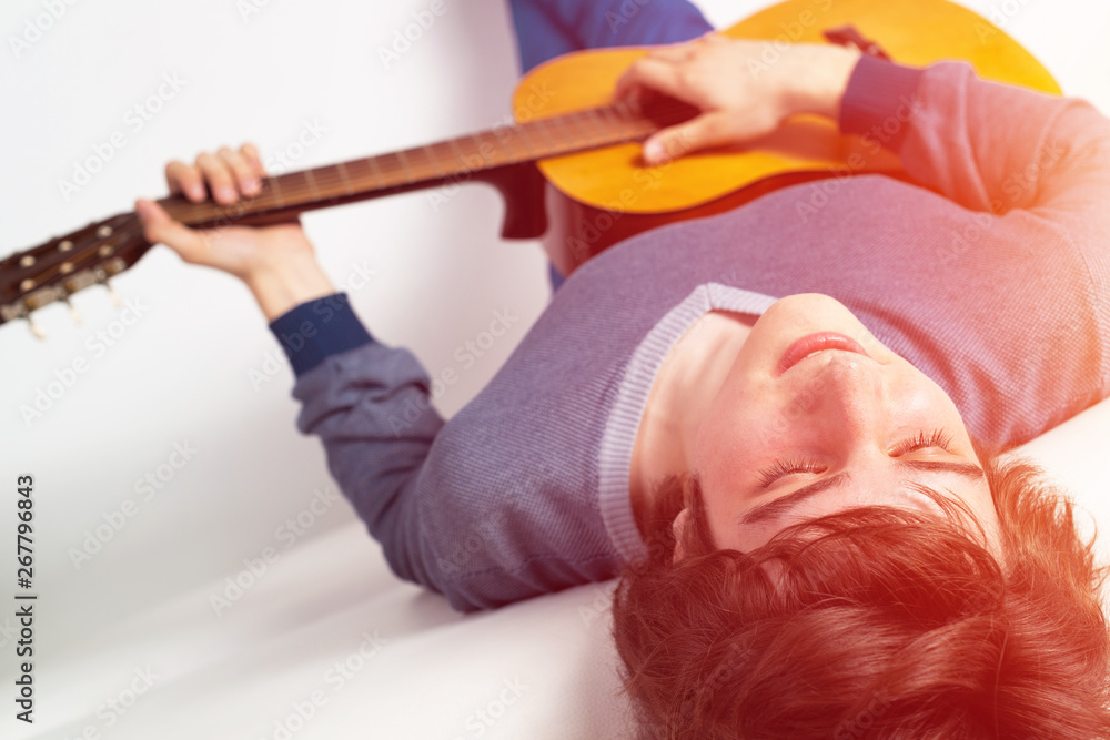 Young man with closed eyes practicing guitar