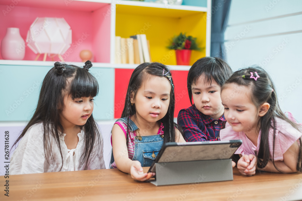 Group of diversity cute kids watching on tablet for lesson in classroom, education concept