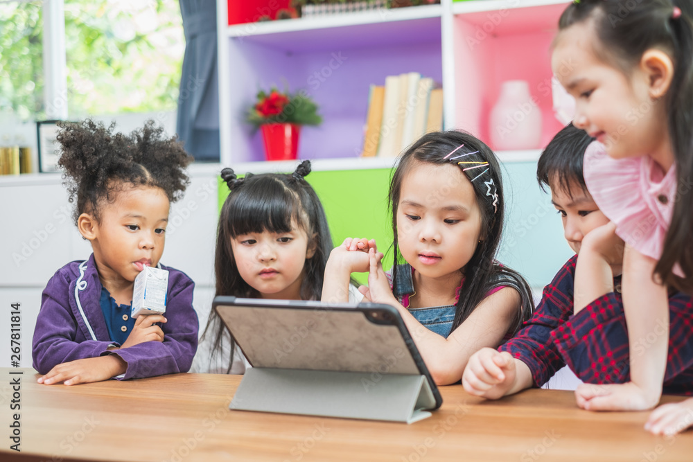 Group of diversity cute kids watching on tablet for lesson in classroom, education concept