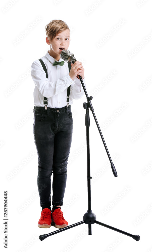 Cute little boy with microphone singing against white background