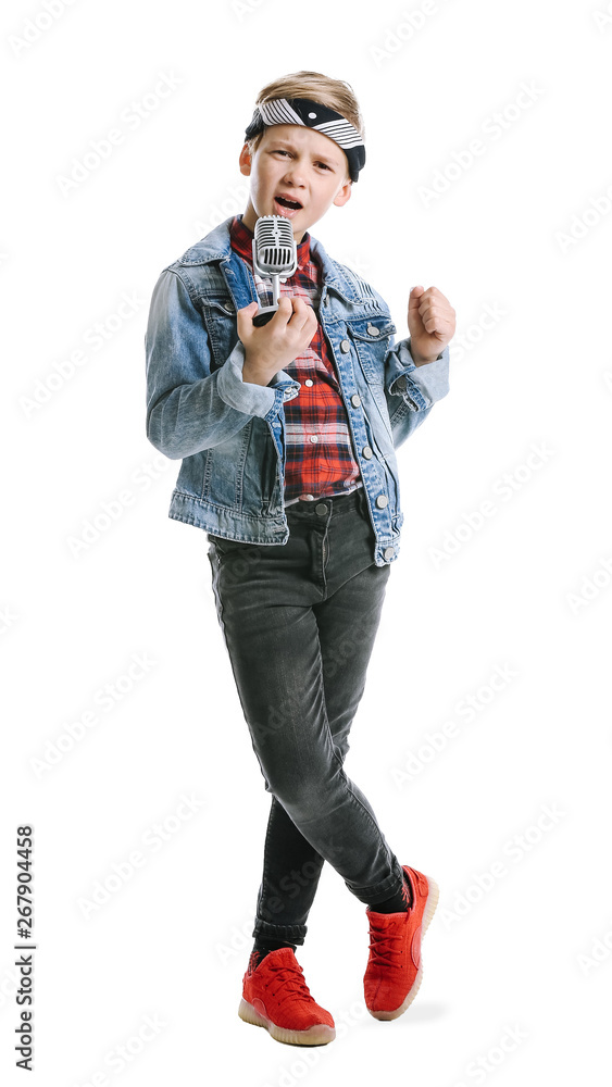 Cute little boy with microphone singing against white background