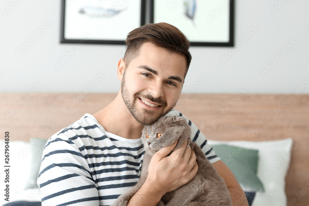 Young man with cute funny cat at home