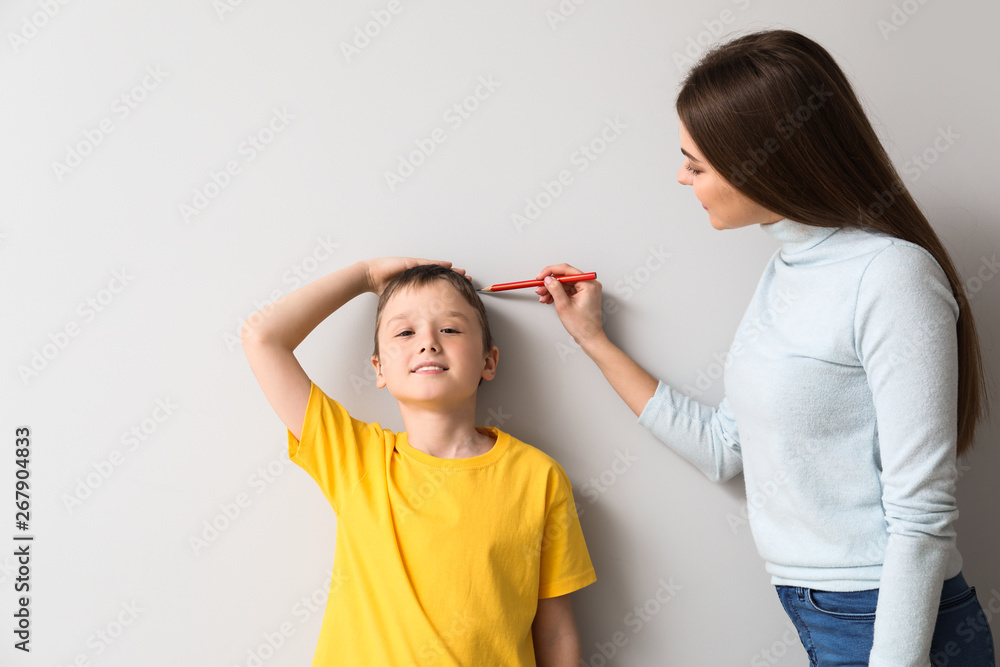 Mother measuring height of her son near wall