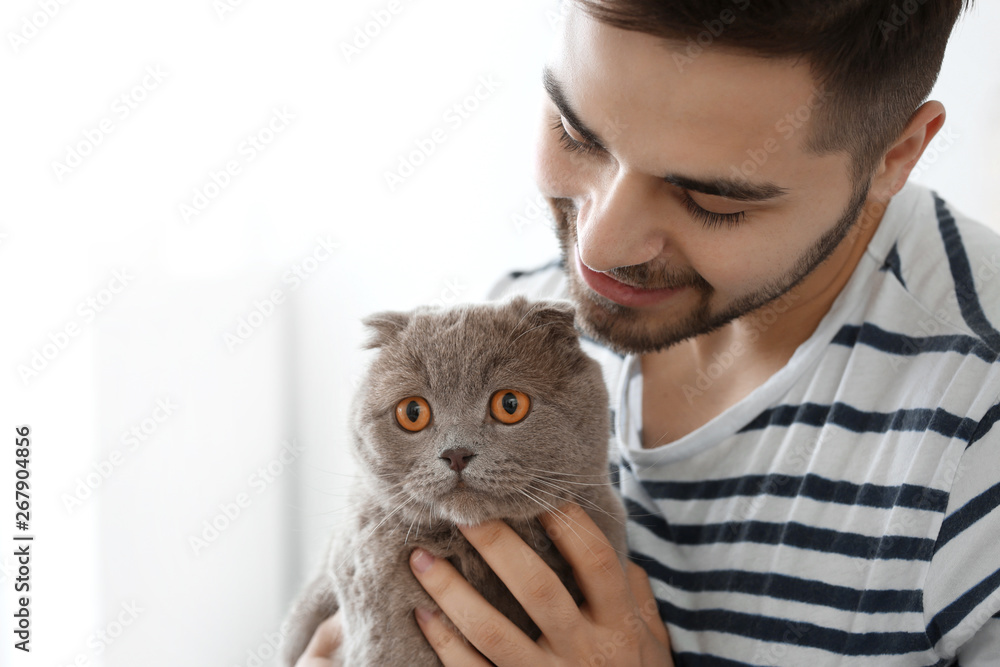 Young man with cute funny cat at home