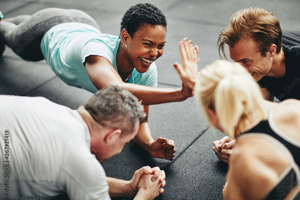 Two laughing women high fiving while planking at the gym