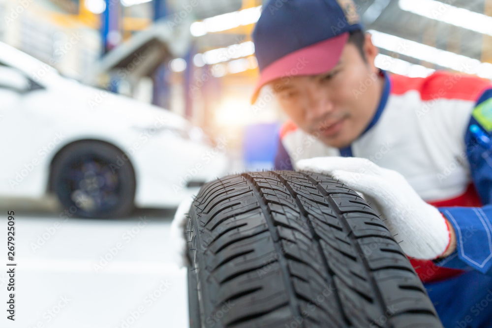 Asian man mechanic in uniform posing on spare wheel, Spare tire car, Seasonal tire change, Car maint