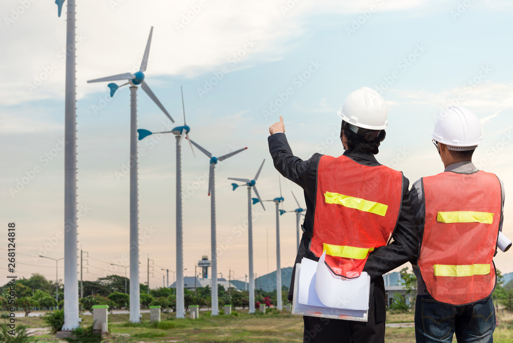 Young business man and engineer with solar panel and wind generators power plant construction site b