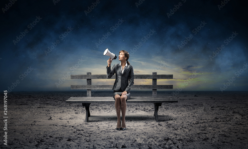 Business woman with megaphone on wooden bench