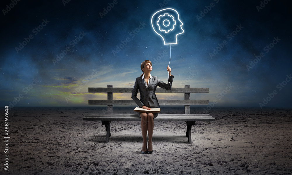 Young woman holding open book on bench