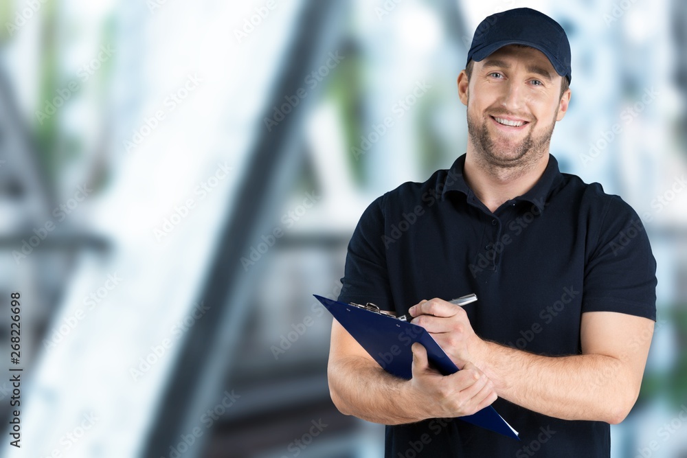 Delivery man with clipboard on light background