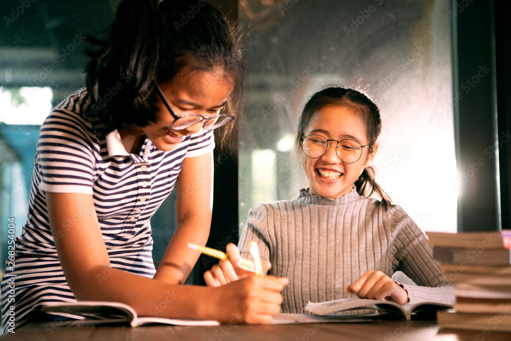 two asian girl laughing with happiness emotion doing school home work in living room