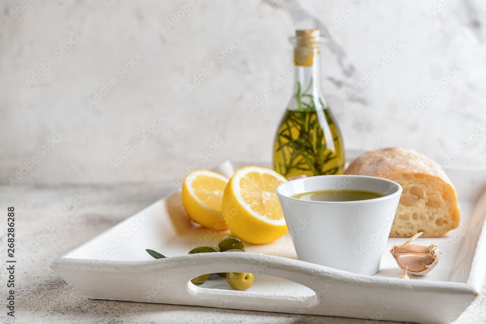 Tray with tasty olive oil and bread on light table