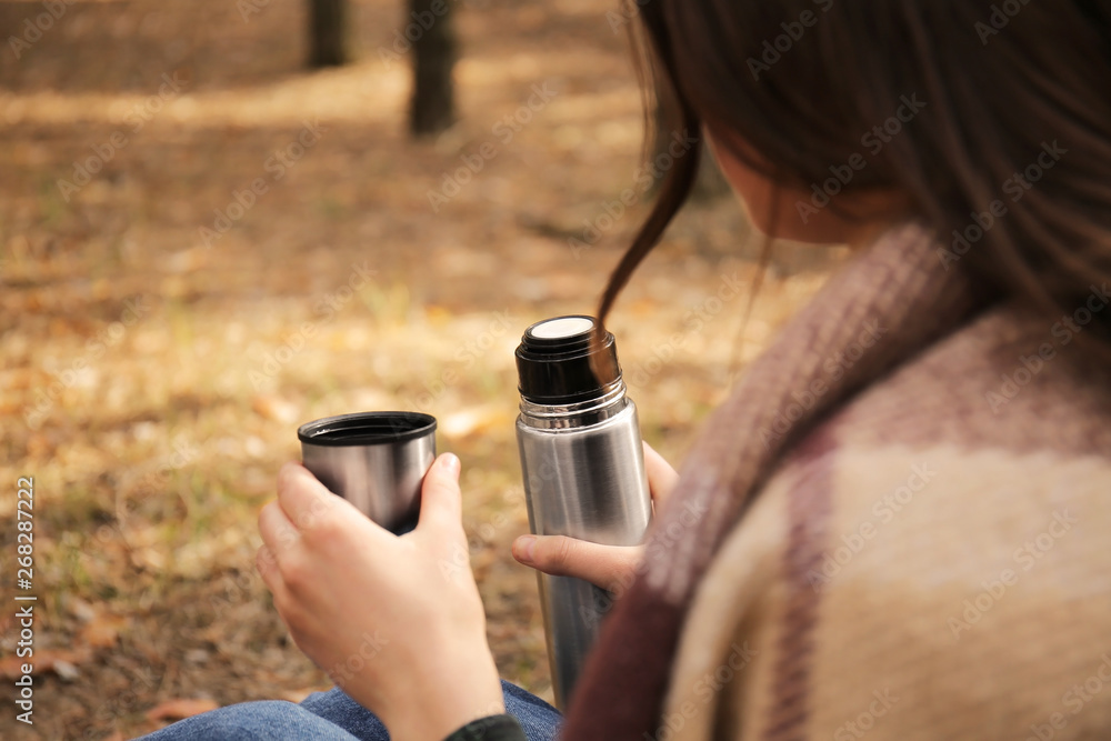 在森林里用保温瓶喝热茶的女人