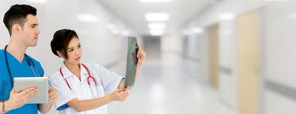 Female doctor looking at x ray film while discussing with another doctor holding a tablet computer a