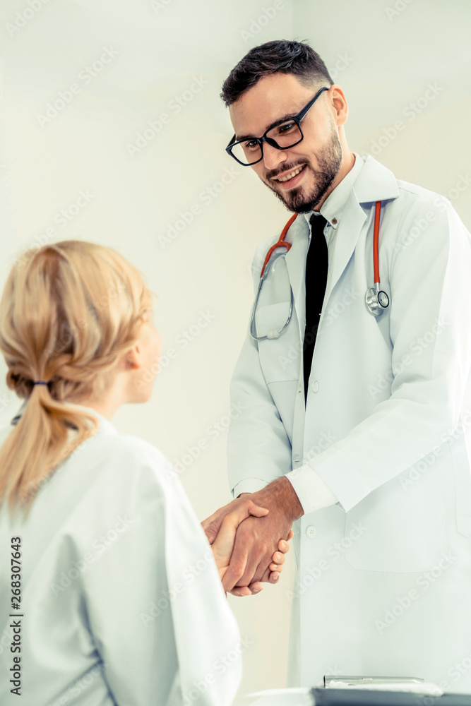 Doctor at the hospital giving handshake to another doctor showing success and teamwork of profession