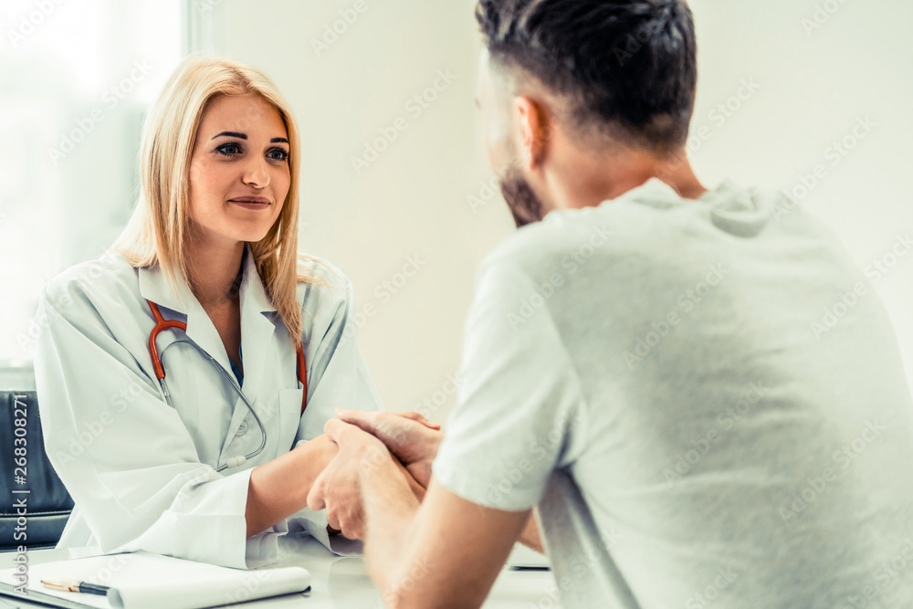 Woman doctor doing handshake with male patient in hospital office room. Healthcare and medical servi