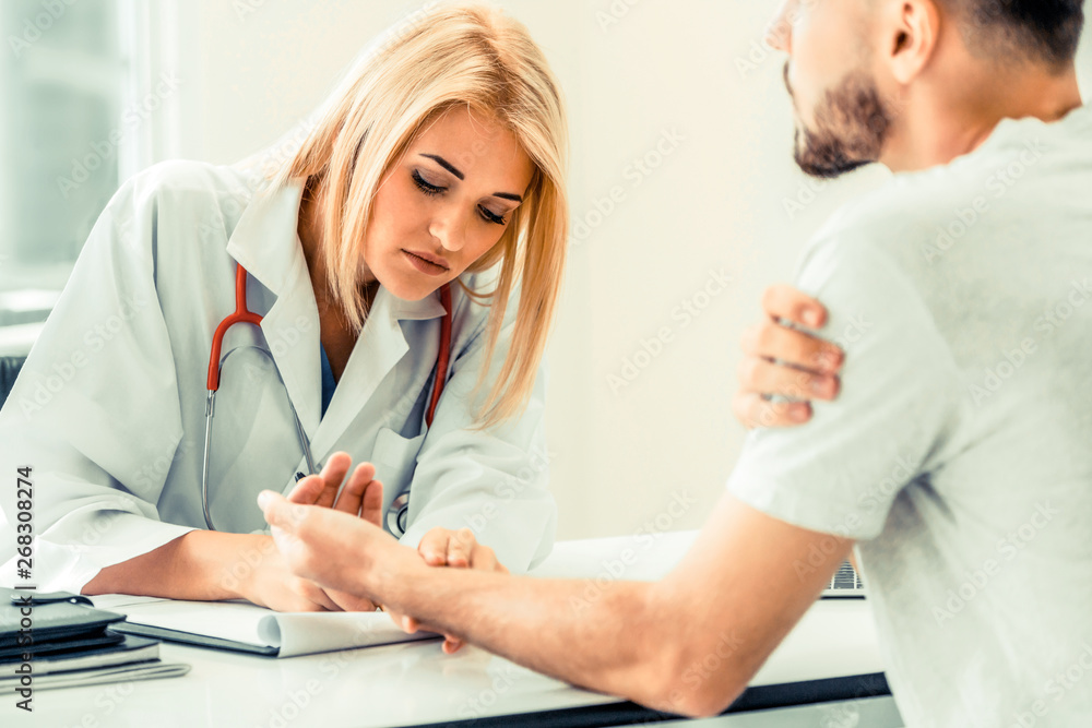 Woman doctor is talking and examining male patient in hospital office. Healthcare and medical servic