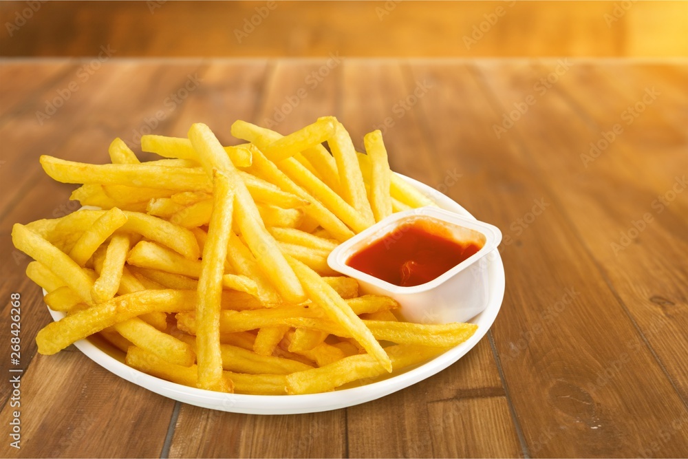 Fresh fried french fries with ketchup on wooden background