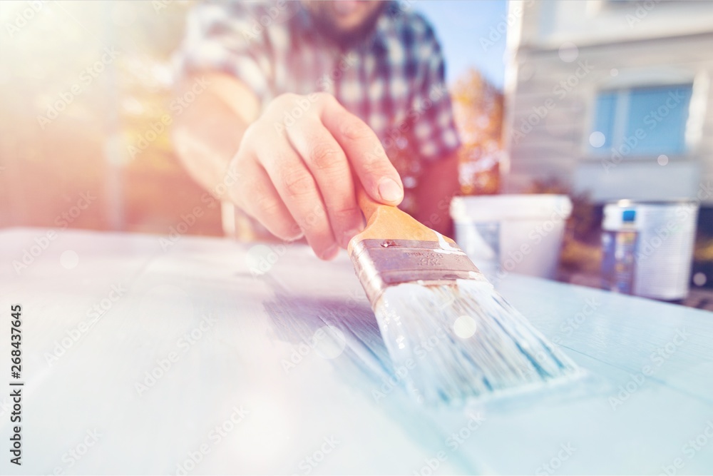 Man with paintbrush painting on the wooden