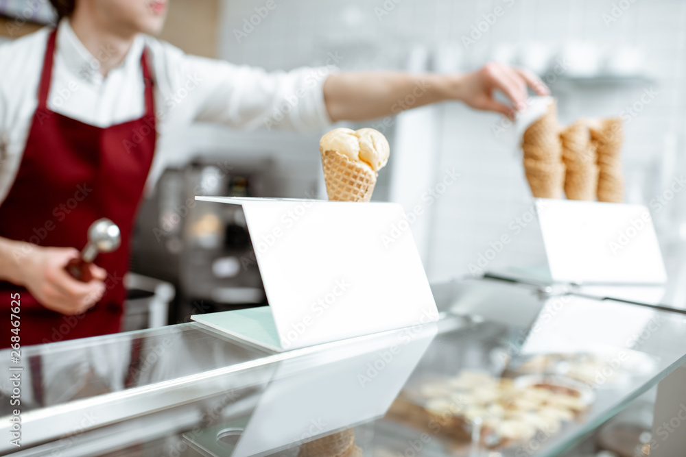 糕点店柜台上华夫饼蛋卷里的冰淇淋，背景是售货员