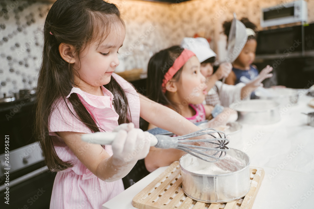 一群孩子正在厨房准备面包店。孩子们正在学习烹饪饼干