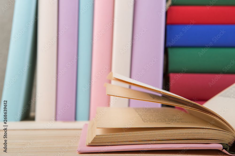 Education and reading concept - group of colorful books on the wooden table, concrete wall blackboar