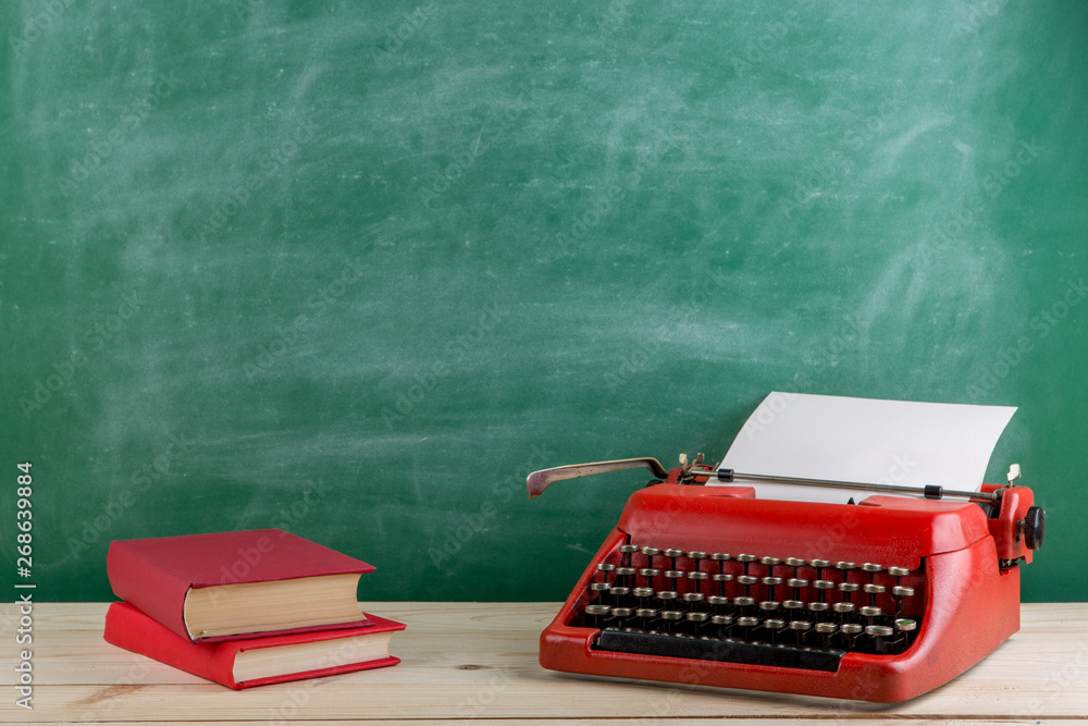 vintage typewriter and books on the table with blank paper on wooden desk