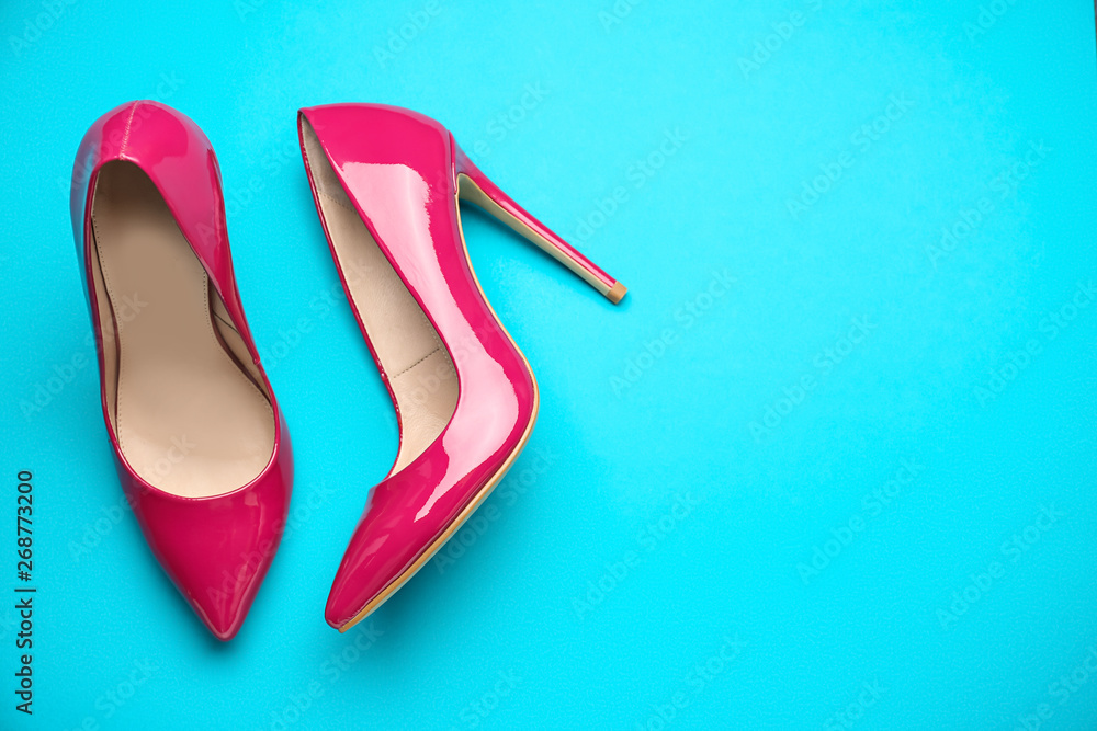 Stylish high heeled shoes on color background