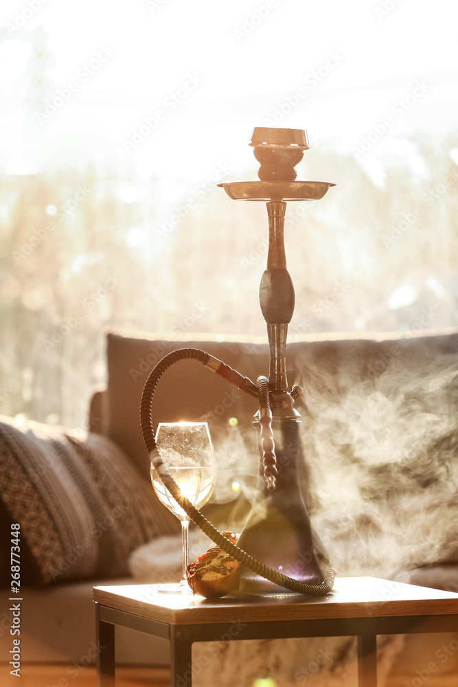 Hookah, pomegranate and glass of alcohol on table in room