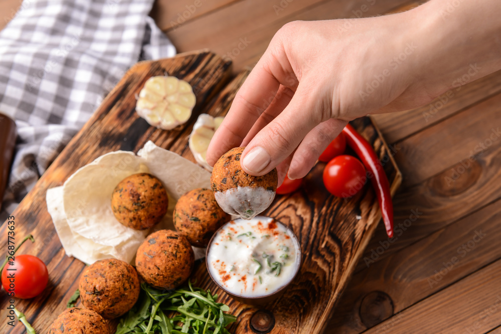 Woman eating tasty falafel balls with sauce, closeup