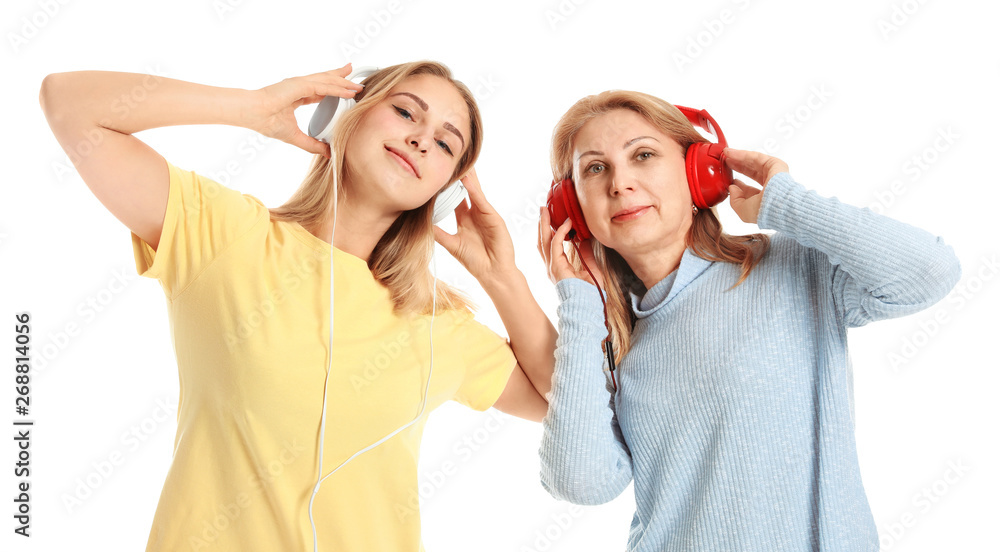 Portrait of happy mother and daughter listening to music on white background