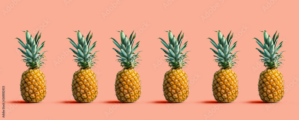 Many pineapples on a solid color background