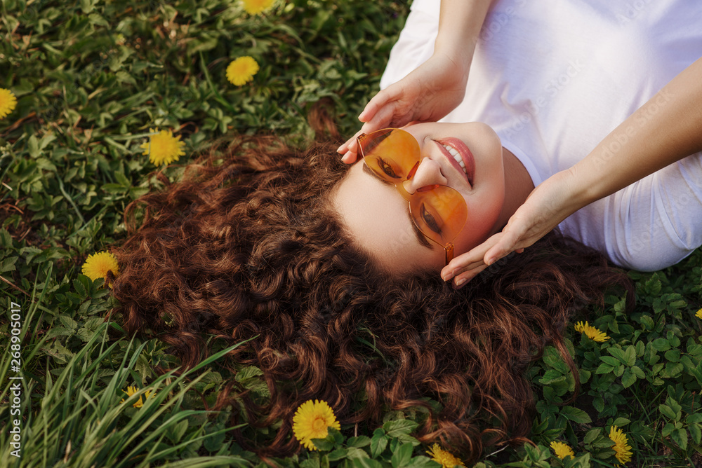 Outdoor flat lay, top view close up portrait of young beautiful happy smiling girl with long curly h