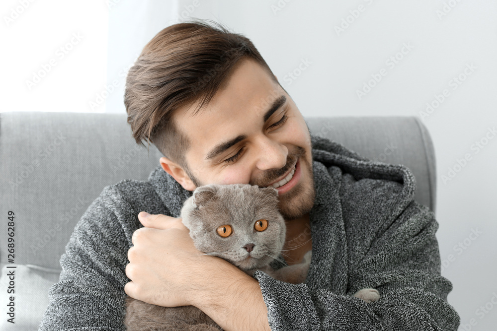 Young man with cute funny cat at home