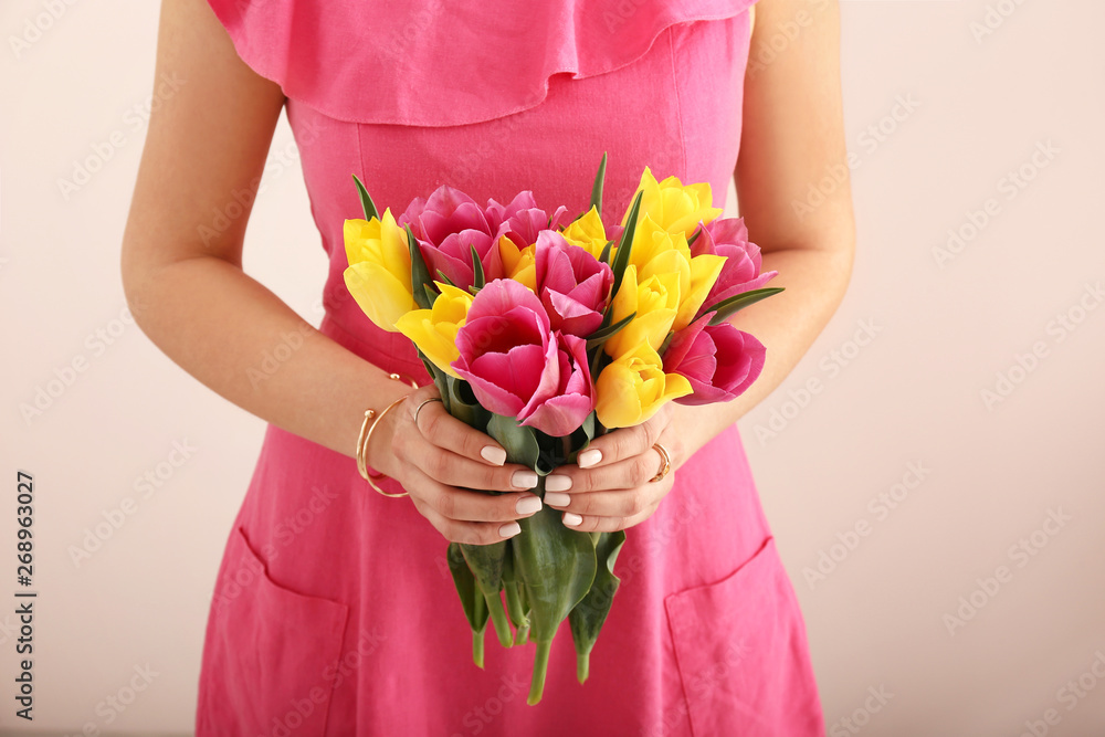 Young woman with bouquet of beautiful tulip flowers on light background, closeup